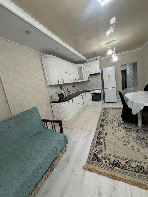a bedroom with a bed and a kitchen with a table at высотка 15 in Aktobe