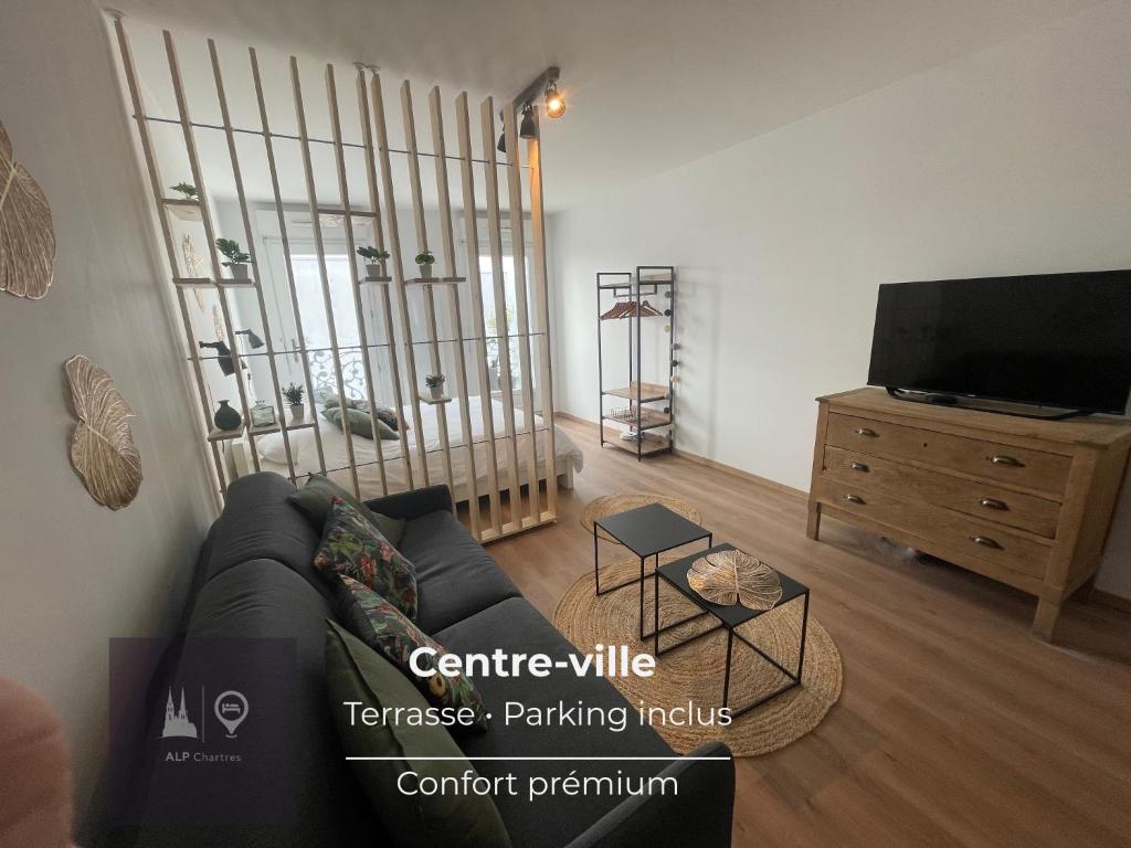 a living room with a couch and a flat screen tv at Studio Terrasse et parking, 4 pers par ALP Chartres in Chartres