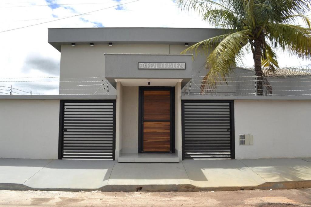 a white house with a palm tree in front of it at Real Grandeza - Studios modernos in Aparecida de Goiânia