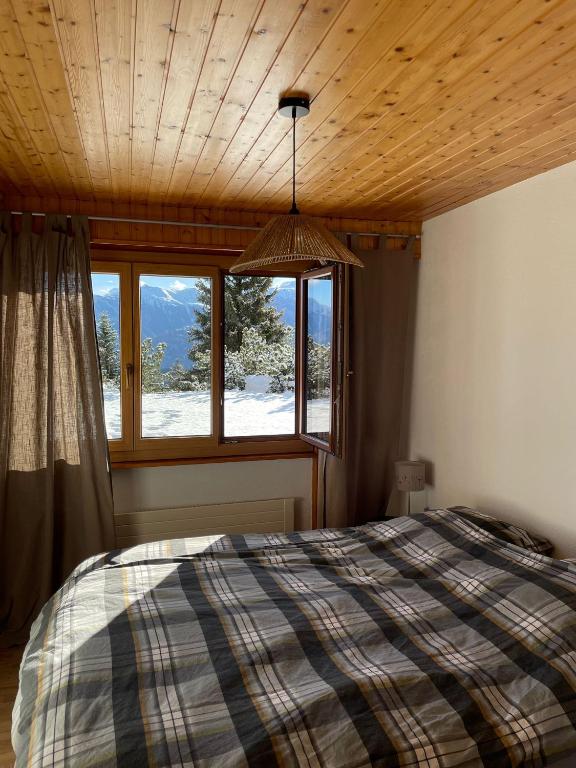 a bedroom with a bed and a large window at Anzère appartement de vacances calme et sympa in Anzère