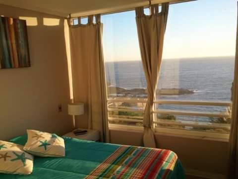 a bedroom with a window with a view of the ocean at Euromarina Dos Reñaca in Viña del Mar