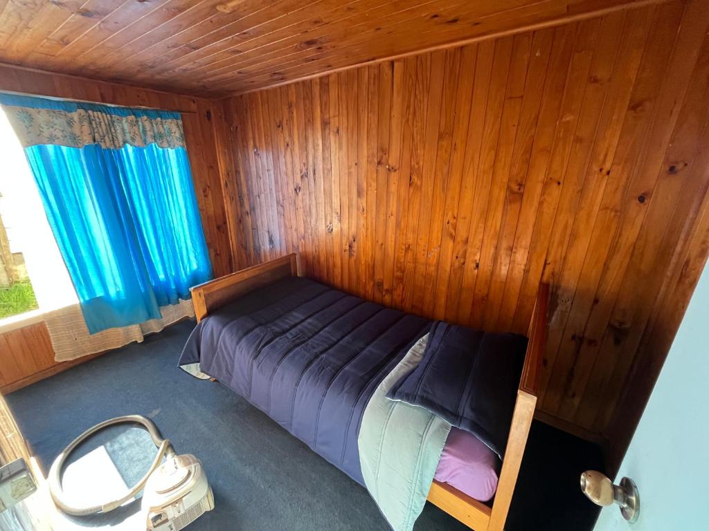 a bedroom with a bed in a wooden wall at Cabañas centro Quellón in Quellón
