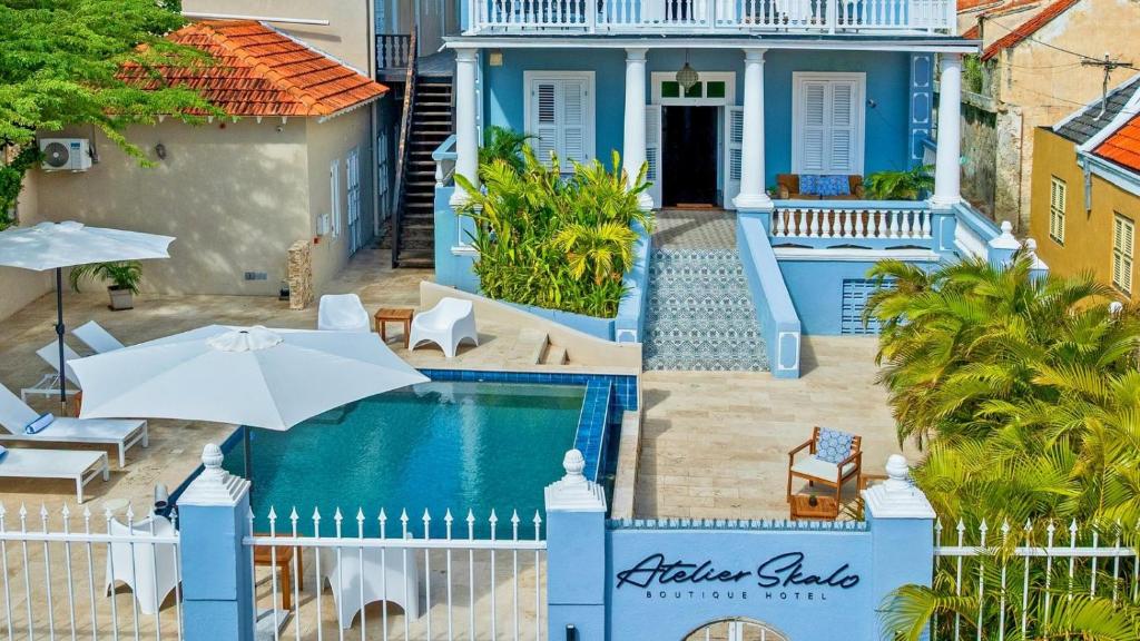 a blue house with a swimming pool and an umbrella at Atelier Skalo Boutique Hotel in Willemstad