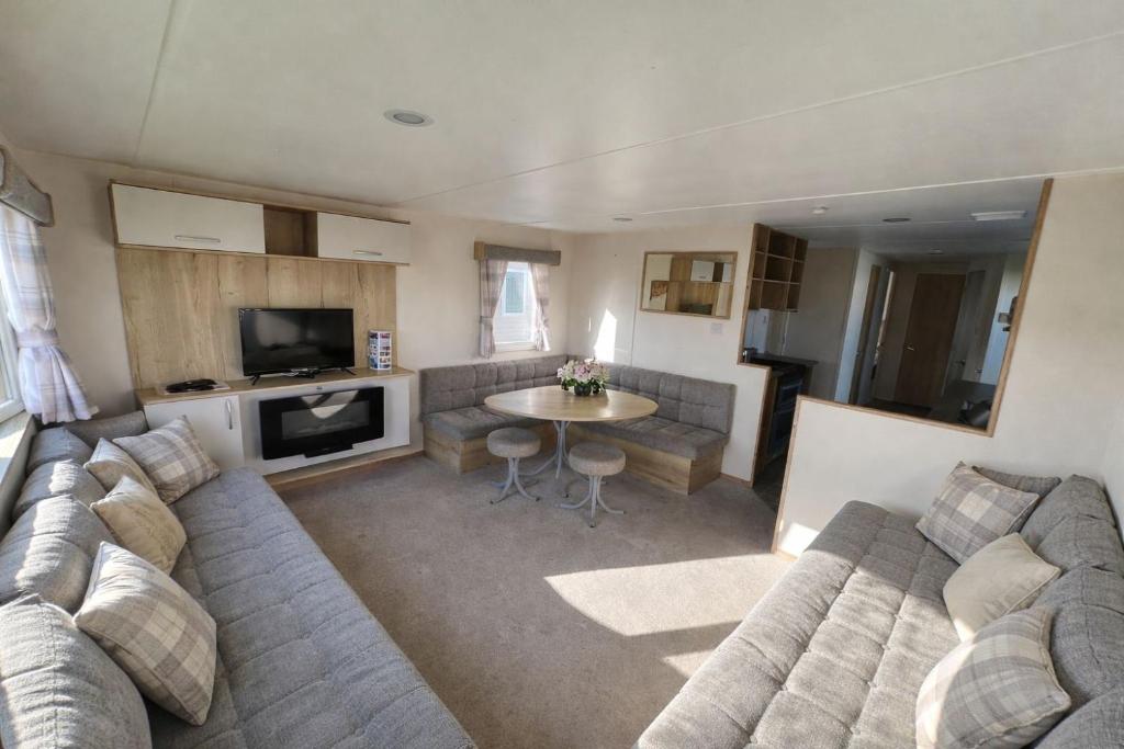 a living room with a couch and a table at Reeva's Resort at Littlesea Holiday Park, Weymouth in Wyke Regis