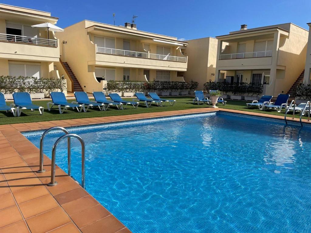 a large swimming pool with blue chairs in front of a building at Vinaros Cala Montero 2 in Vinarós