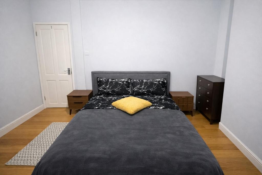 a bedroom with a black bed with a yellow pillow at Midnight Horizon - shared bathroom in Ponders End