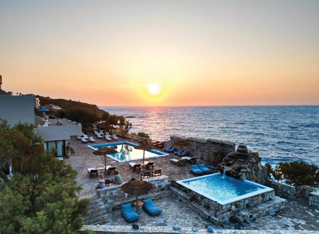 a resort with a pool and the ocean at sunset at Cavos Bay Hotel & Studios in Armenistis