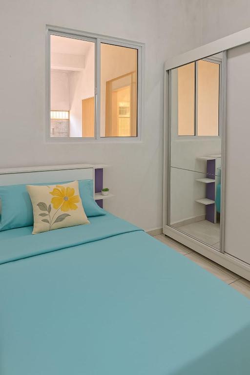 a bedroom with a blue bed with two windows at Doce Lar São Francisco in Cabo de Santo Agostinho