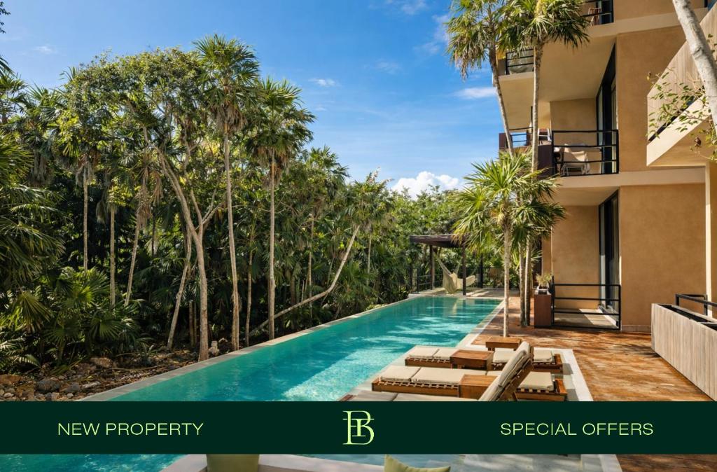 a resort pool with chaise lounges and palm trees at BT Homes - Tankah Bay Tulum - Exclusivos apartamentos con piscina a metros del mar in Tancah