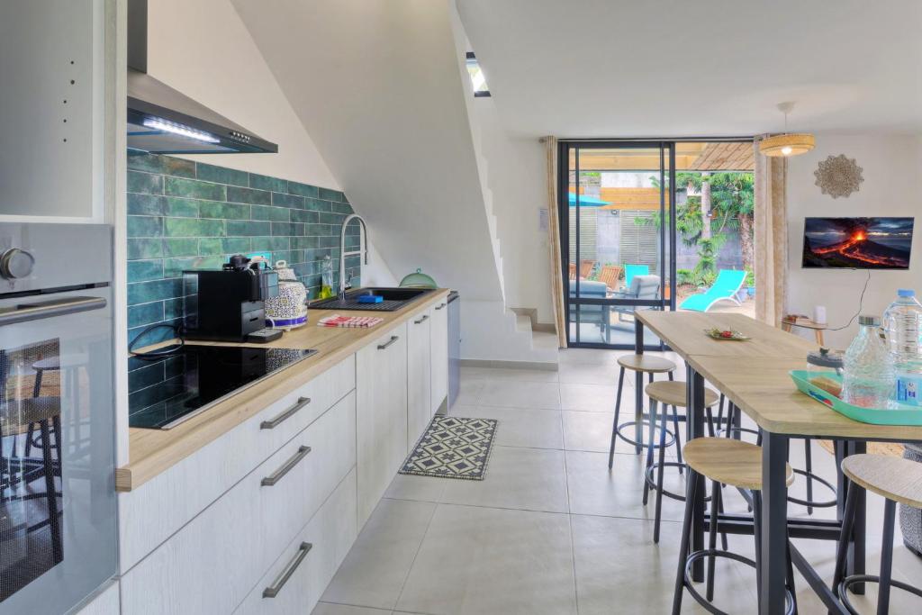 a kitchen with white cabinets and a table with chairs at Dragon Fly Location saisonnier in Le Tampon