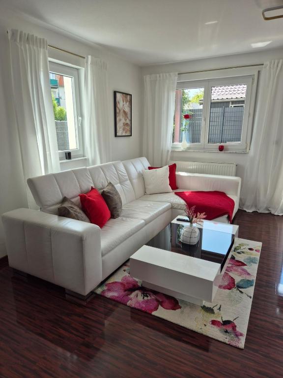 a living room with a white couch and red pillows at Cosima in Hohenroth