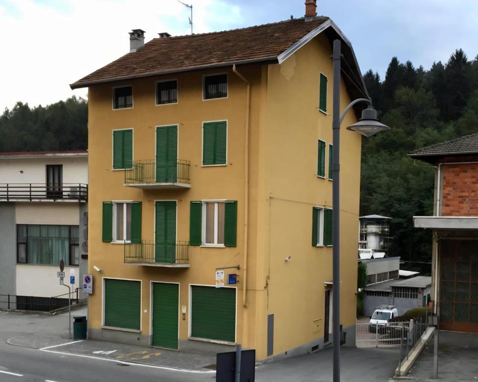 a yellow building with green shutters and a street light at Cà del Cerin in Trivero