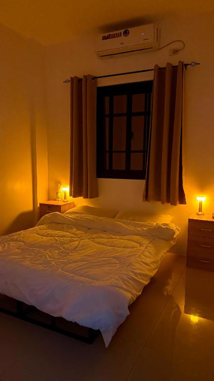a bedroom with a bed and a window and lights at Aey Mabini Homestay in Mabini