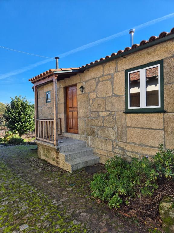 a small stone house with a wooden door and stairs at Casinha do Pátio in Nogueira do Cravo