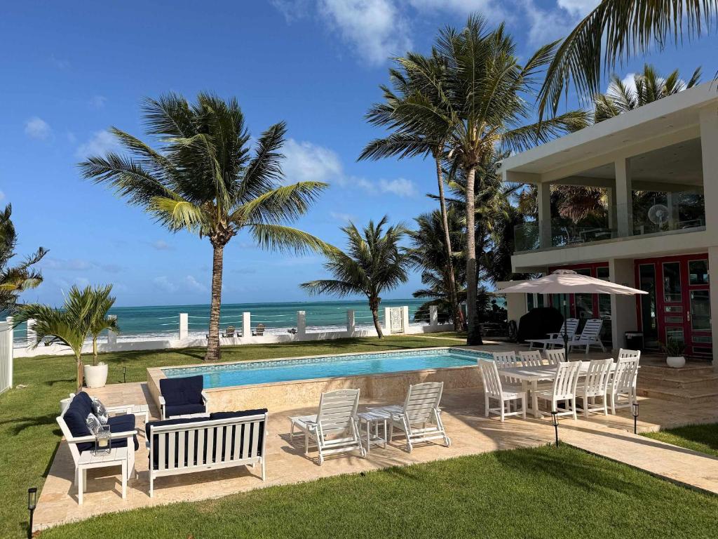 a house with a pool and chairs and the ocean at Beachfront Spacious Luxury Villa Private Pool in Fortuna