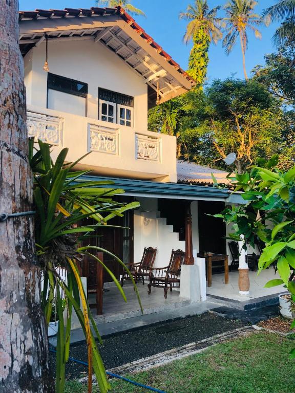 a house with chairs in front of it at Coco Breeze Villa in Talpe