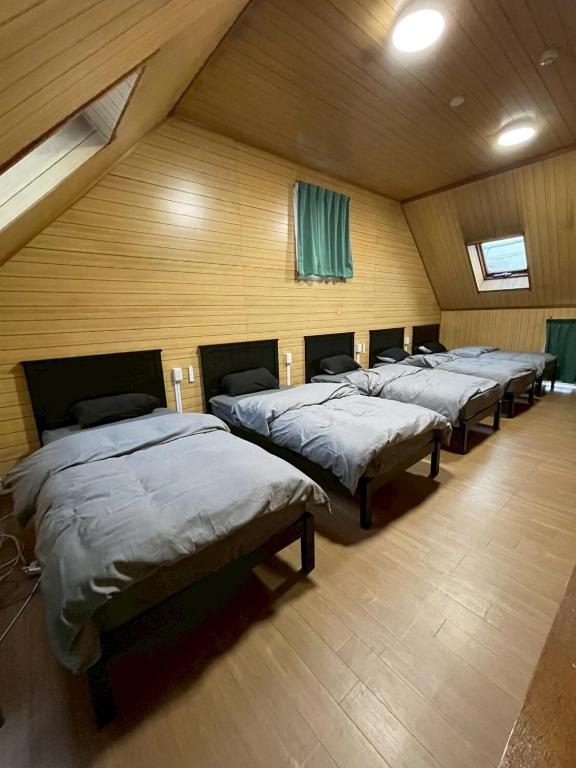 a row of beds in a room with wooden walls at Modern style old house in Nagoya