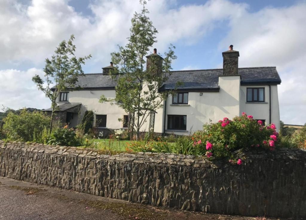a white house with a stone wall at 16th Century Devon Farmhouse Stunning Views in Winkleigh