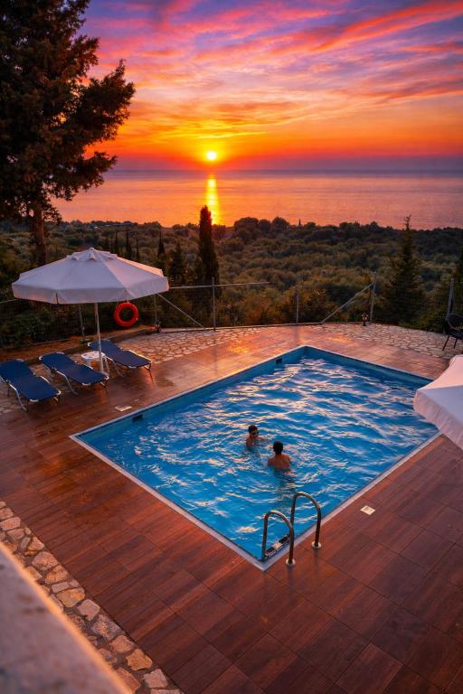 two people in a swimming pool with the sunset in the background at Villa Vera in Agios Nikitas