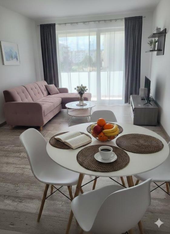 a living room with a table with a bowl of fruit on it at Caskada Modern Apartments 2 NOWY APARTAMENTOWIEC WINDA in Słupsk