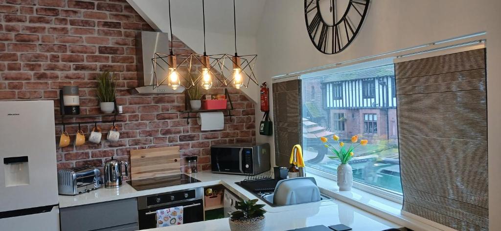 a kitchen with a sink and a brick wall at Seaside Apartment in Moreton