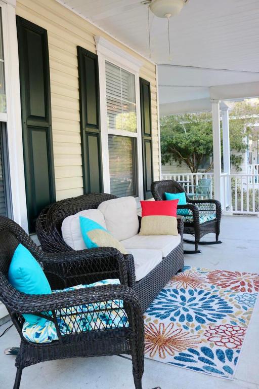 a porch with wicker chairs and a couch on a porch at Happy in Old Town Bluffton in Bluffton