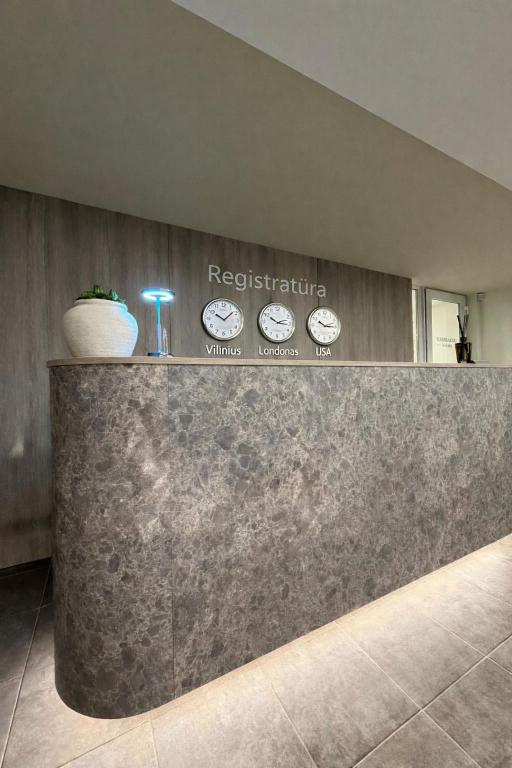 eine Lobby mit drei Uhren an der Wand in der Unterkunft Žilina in Marijampolė