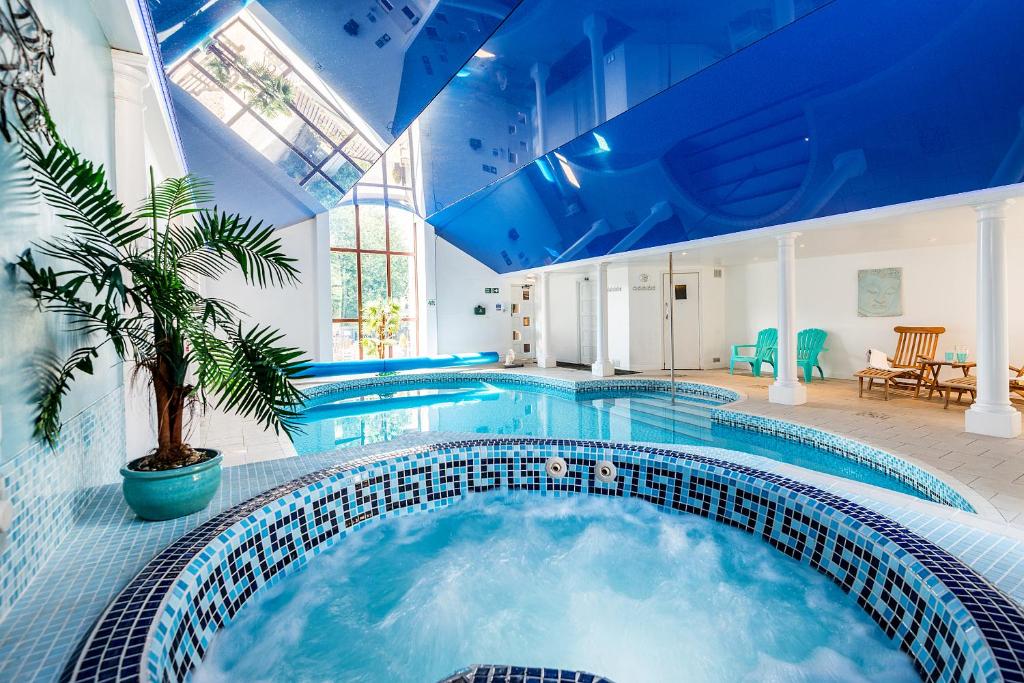 a large swimming pool with a blue ceiling at Smugglers Cottage converted Barn with Pool & Jacuzzi NR Lyme Regis in Whitchurch Canonicorum