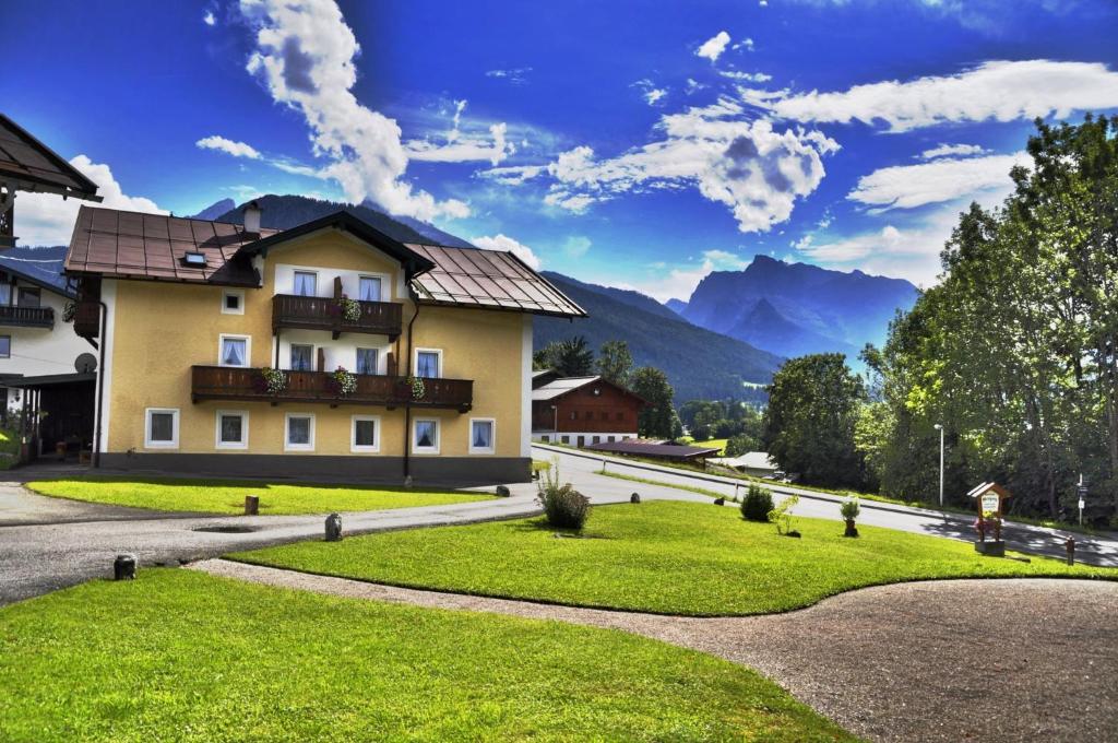 une maison dans les montagnes avec une pelouse verdoyante dans l'établissement Pension Gregory, à Schönau am Königssee
