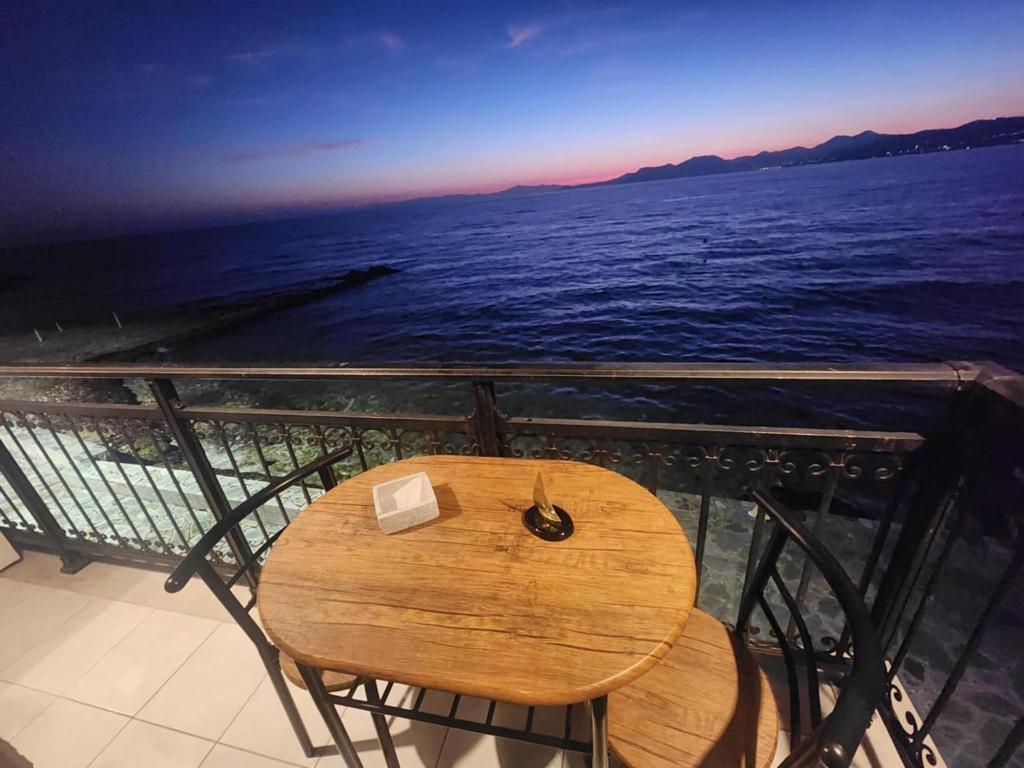 a wooden table on a balcony with the ocean at Blue Sea Suite Avlakia in Avlákia