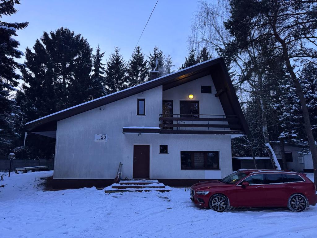 a red car parked in front of a house in the snow at Noclegi na Asfaltowej in Sulejówek