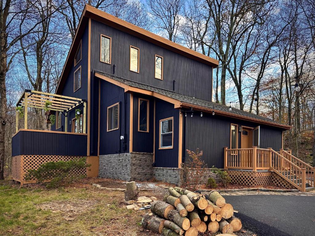 a blue house with a pile of logs in front of it at Blackwood Cabin Pocono in Pocono Farms East