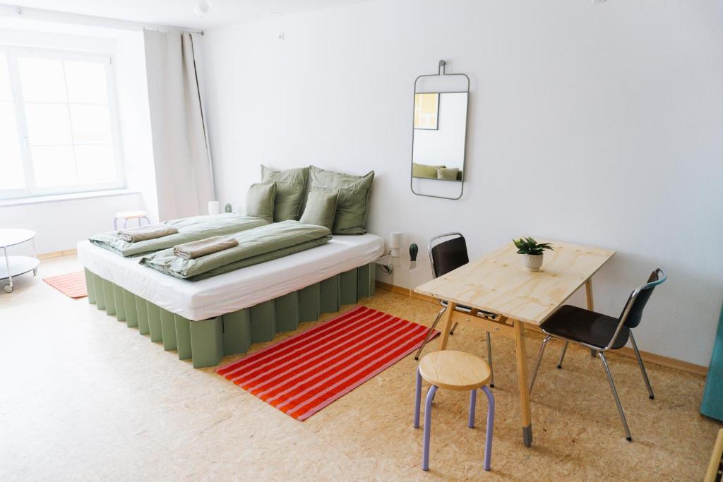 a bedroom with a bed and a table and a desk at raum life - Design Apartment mit Küche in der Altstadt in Regensburg