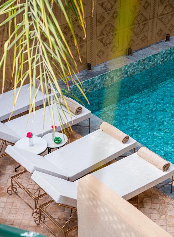 a pool with white benches next to a swimming pool at Kasbah La Moun - The Art Of Hospitality in Marrakesh