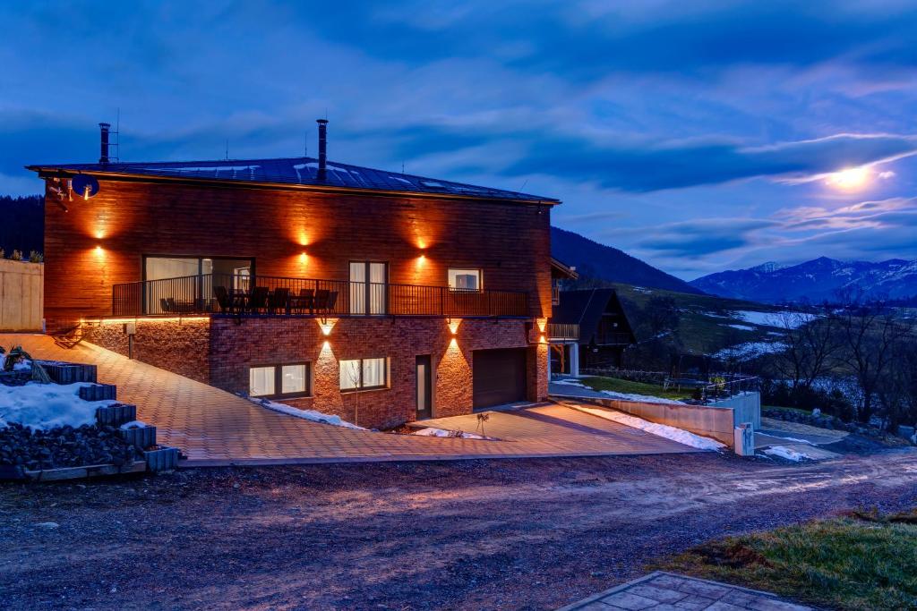 a house with lights on the side of it at night at TRIA House Liptov in Ižipovce