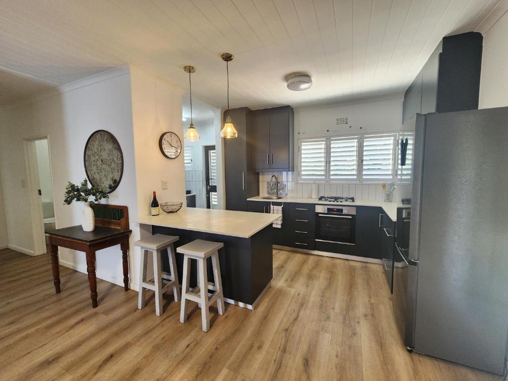 a kitchen with black cabinets and a table and chairs at Welgelegen Self Catering in Malmesbury