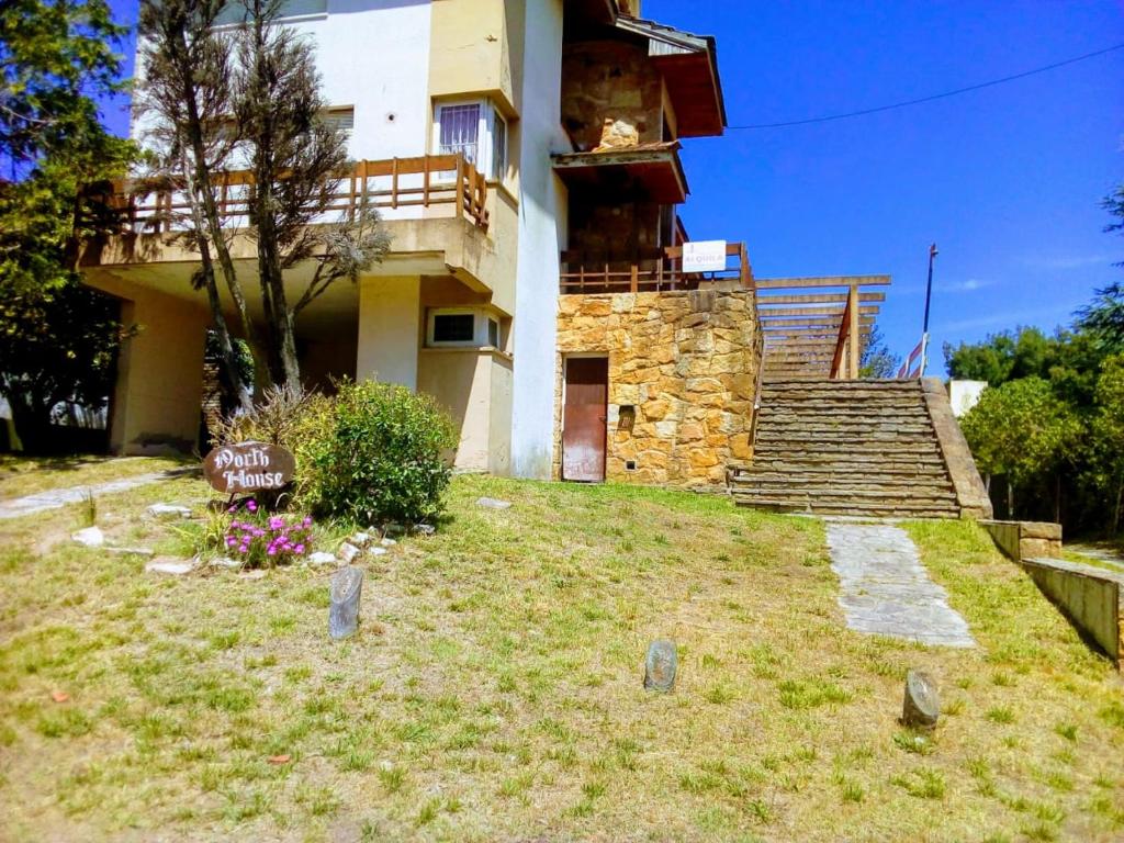 a house with stairs and a grassy yard in front of it at PH con cochera cubierta cerca de la playa in Villa Gesell