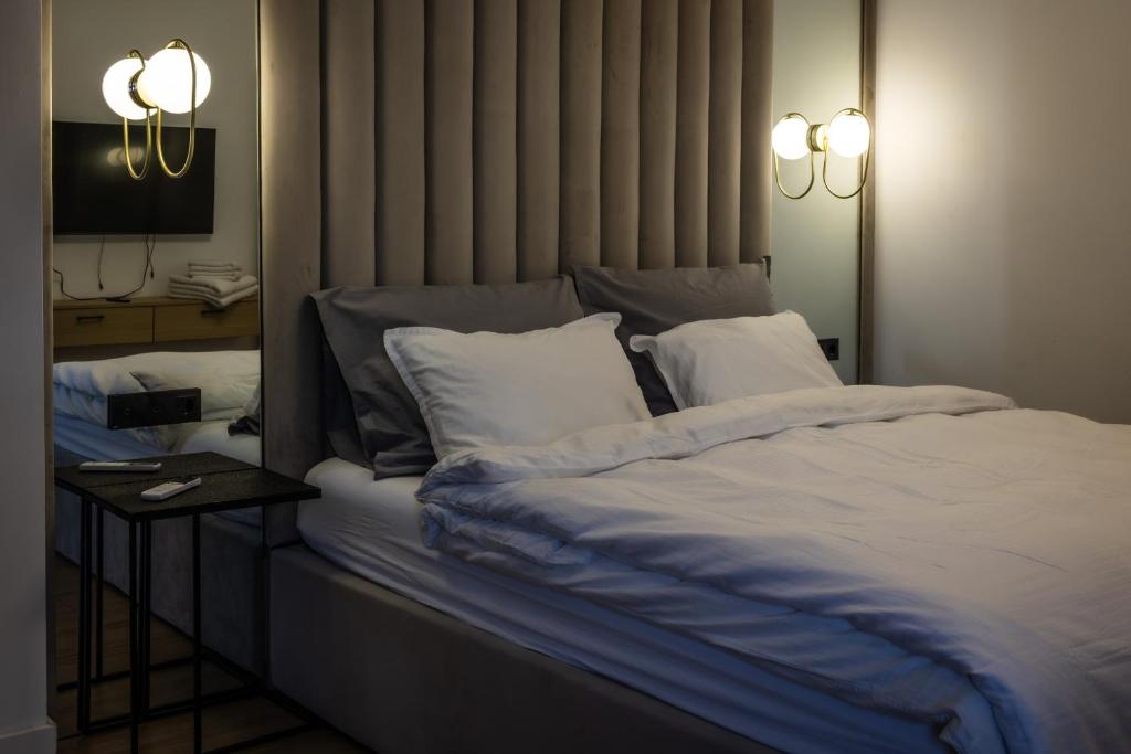a bed with white sheets and pillows in a room at Mirror Apartments in Satu Mare