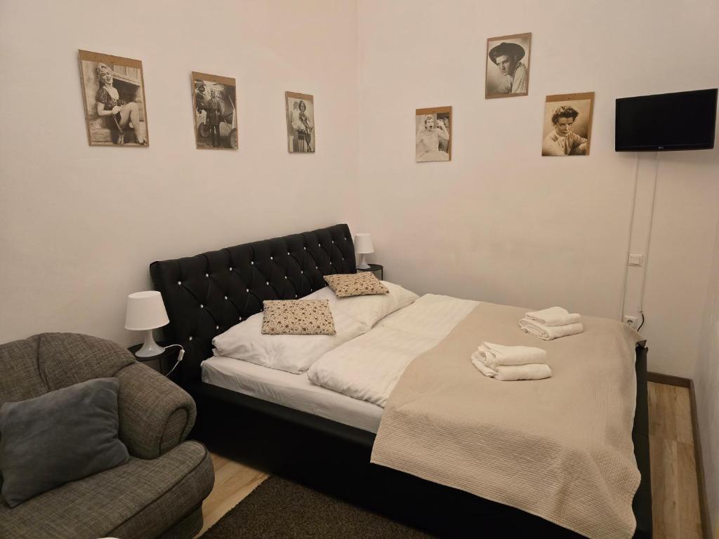 a bedroom with a bed and a chair and pictures on the wall at Budapest B&B Bed and Breakfast in Budapest
