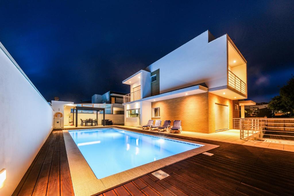 a villa with a swimming pool in front of a house at Nazare House4you in Nazaré