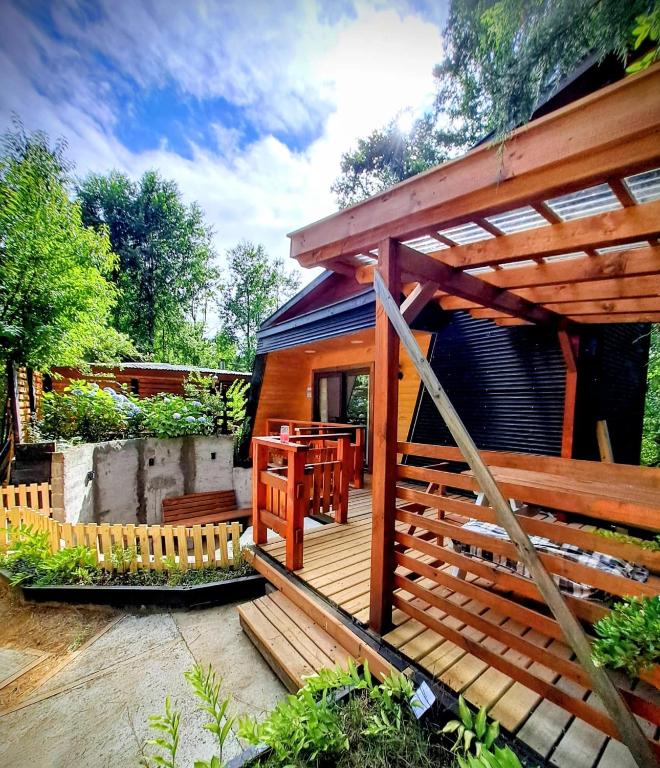 a small wooden cabin with a wooden deck at Casa Arrayan in Coñaripe