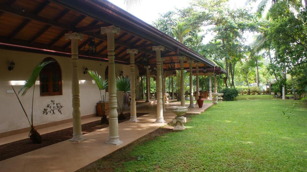 a porch of a house with a green yard at Dedduwa Boat House in Bentota