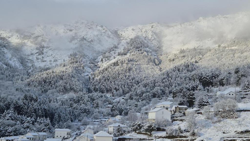 a snow covered mountain with a town and houses at H(a)ver as Faias in Manteigas