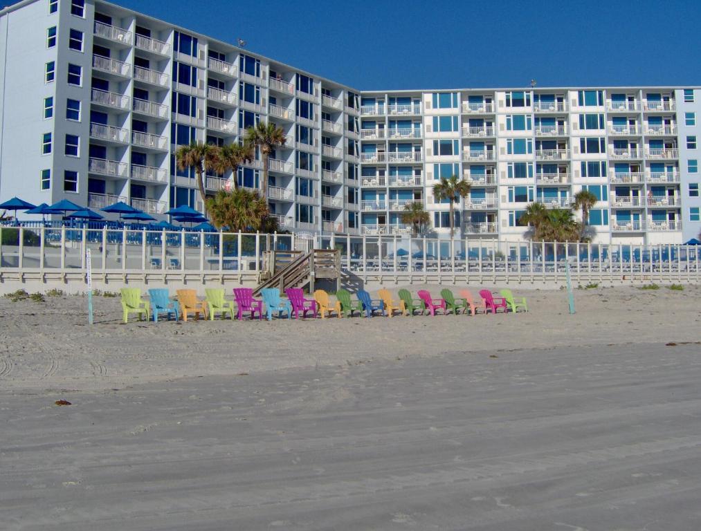 Islander Beach Resort - New Smyrna Beach في نيو سميرنا بيتش: صف من الكراسي على الشاطئ امام الفندق