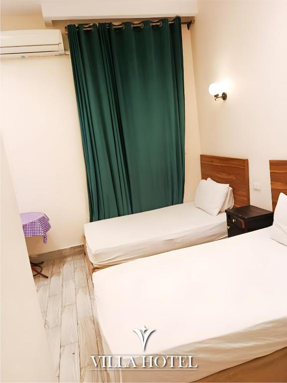 two beds in a room with a green curtain at Villa Downtown Hotel in Cairo