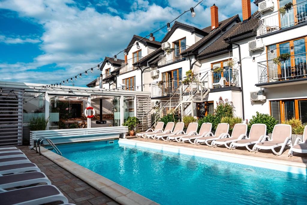 a swimming pool with lounge chairs next to buildings at Orbisa Bis w cenie Basen podgrzewany Sauna Jacuzzi Rowery Parking Klimatyzacja Opcja śniadań in Łeba