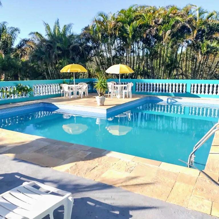 a swimming pool with two chairs and umbrellas at Pousada Recanto Águas Vivas com Piscina Aquecida e Lazer Completo próximo a Sorocaba in Turvo dos Góis