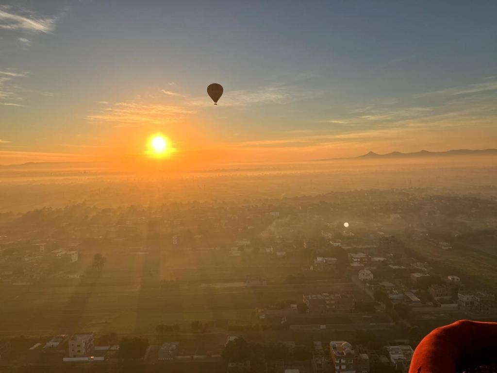 a hot air balloon flying over a city at sunset at sunrise house in Luxor