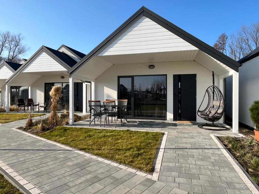 a house with a patio with a table and chairs at Domki BAMBINO in Sarbinowo