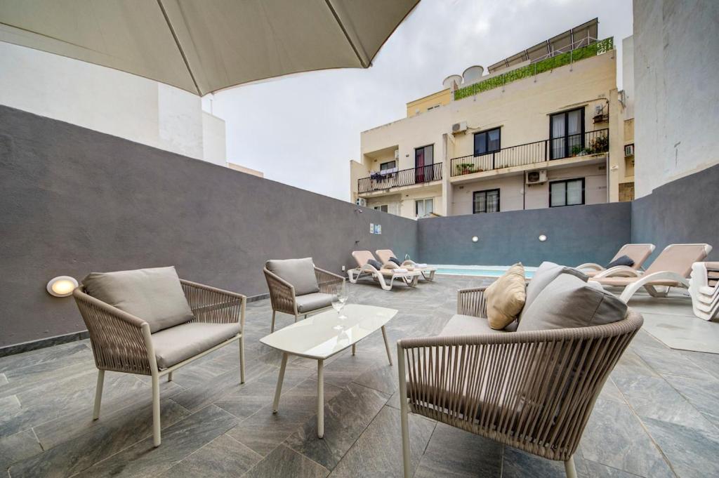 a patio with chairs and a table and an umbrella at Central Oasis - Private Pool & Lounge Area in Santa Vennera